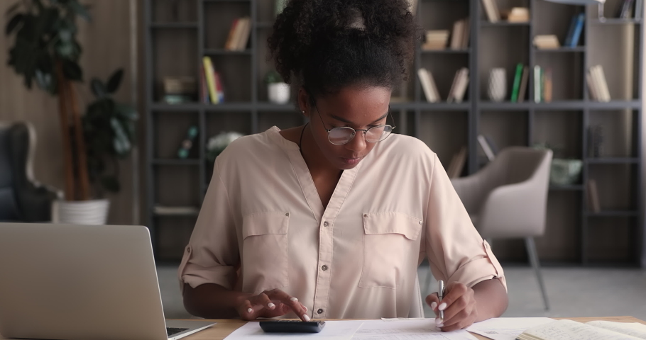 African woman using calculator and laptop app calculate costs, incomes, expenses, estimate budget for project, accountant conduct financial inspection, summarize total sum. Finance management concept | Shutterstock HD Video #1065238069