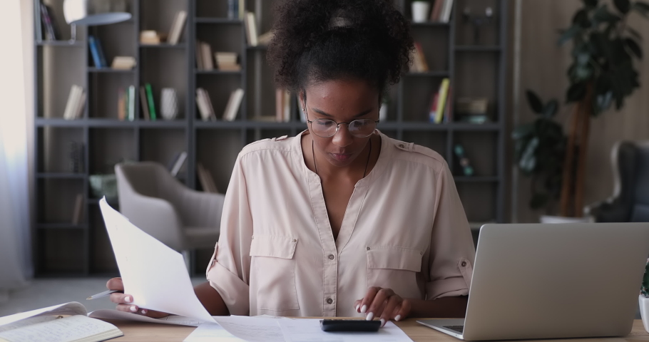 African female accountant sit at desk use calculator calculates finances feels stressed about mistake in financial document. Lack of money, bookkeeper experiences troubles due error in report concept | Shutterstock HD Video #1065238075