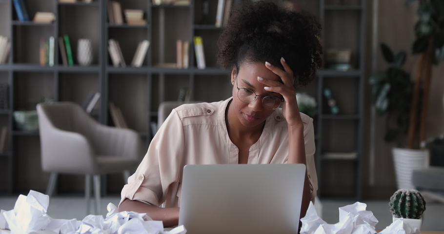Stressed african business woman sit at desk with laptop and crumpled papers, feels tired take off glasses, having concentration problem, lack of ideas, writers block, creative crisis, deadline concept Royalty-Free Stock Footage #1065238129