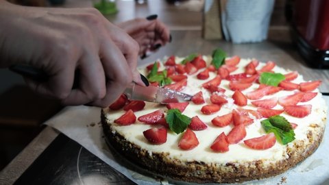 Women's hand is cutting freshly cooked homemade strawberry cheesecake New York, close-up, 4k