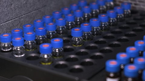 Automated conveyor line of auto sampler in HPLC system. Vials with blue caps in the tray. Testing of vaccine and pharmaceuticals
