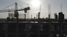 Construction workers (builders) silhouettes are on the rooftop of a residential building under construction (in a course of building). Aerial side view - Powered by Shutterstock - Get 15% off with code: PIKWIZARD15
