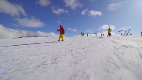 Friends skiing together on a sunny day. Skier throwing snow in camera.