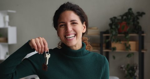 Head shot beautiful single woman smiling showing bunch of keys into camera. Happy homeowner portrait, relocation move day celebration, bank loan offer for young people, rented flat and tenancy concept