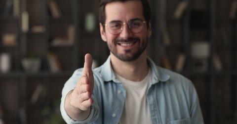 Confident businessman in glasses standing in office room smile reaching out his arm for handshake, closeup view. HR manager employer welcomes in company new worker, greeting, first impression concept