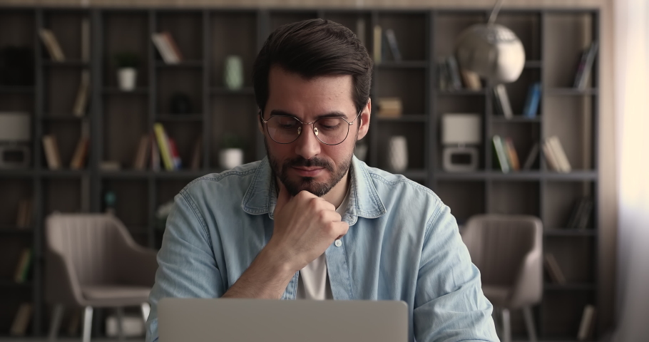 Pensive business man in glasses distracted from laptop work pondering looks in distance. Thoughtful employee search creative ideas, think on challenge seated at desk. Planning, business vision concept Royalty-Free Stock Footage #1065266671