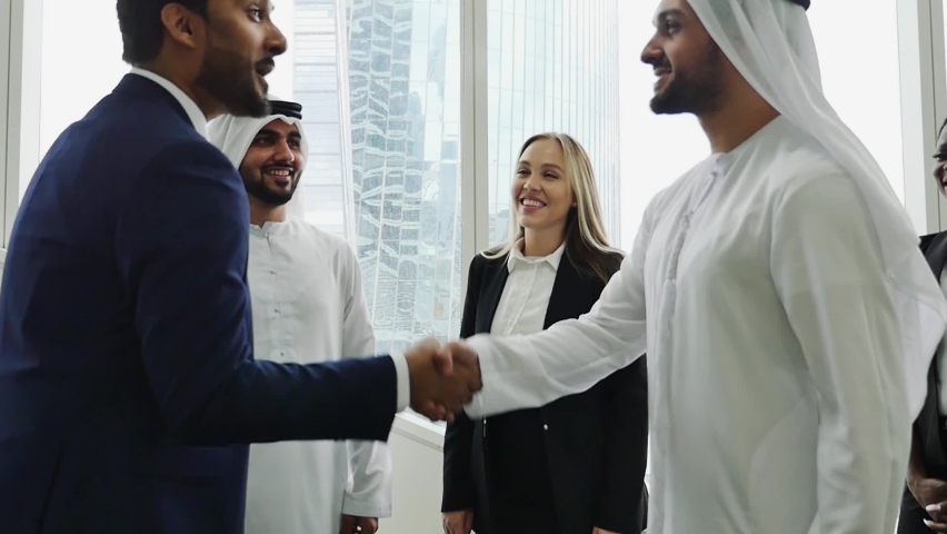 Mixed business team in Dubai. Business meeting with men wearing kandura and western people in the office | Shutterstock HD Video #1065278812
