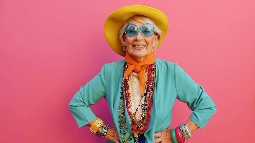 Cinematic footage of an old italian woman having fun on colored background. Happy grandmother with vibrant colored fashion looks Royalty-Free Stock Footage #1065278992