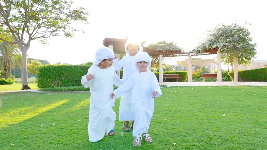 Kids playing outdoor on the meadow. Children wearing traditional united arab emirates kandura having fun Royalty-Free Stock Footage #1065279118