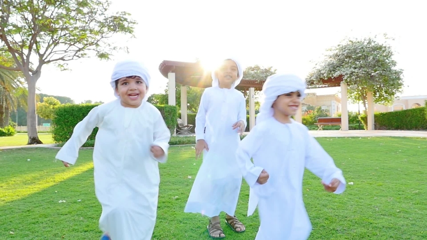 Kids playing outdoor on the meadow. Children wearing traditional united arab emirates kandura having fun | Shutterstock HD Video #1065279118