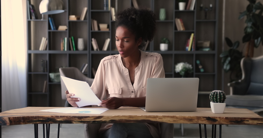 African ethnicity female manager prepare financial report making presentation writes notes or corrections do paperwork seated at modern workplace in office alone. Banking, management, finances concept Royalty-Free Stock Footage #1065279418