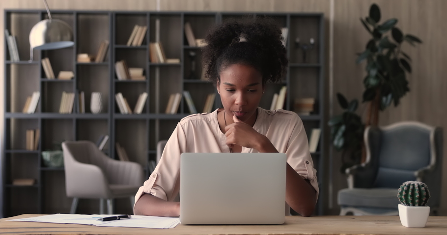 African woman working on financial paperwork seated at workplace using laptop app looks concentrated while makes task, prepare, check report having fruitful workday. Student learning process concept | Shutterstock HD Video #1065279421