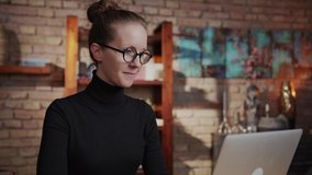 Smart woman in glasses working at home with laptop computer sitting at desk in home office.