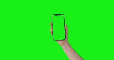 Woman hand holding the smartphone on green screen chroma key background.  Phone mock-up for your product. The iPhone 12 Pro Max model in vertical orientation portrait mode. 2021 - USA, California