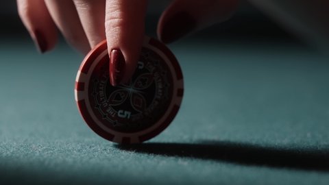 Woman spinning a poker chip on a green table. Lady luck thinking. Red nails on a red casino chip. Business success concept, jackpot.