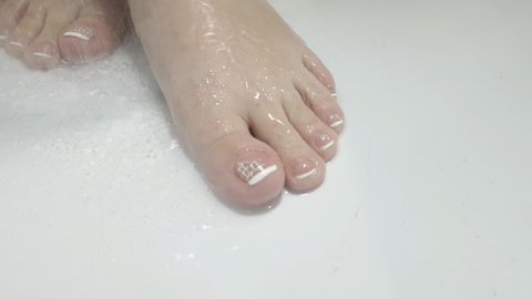 beautiful women's feet under water in the shower, skin care