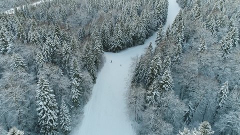 Aerial shot of a winter scene in the mountains and a father learning his kid how to ski on the ski slopes