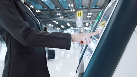 Business woman self check-in and printing boarding pass on kiosk automatic check-in machine in airport departure terminal