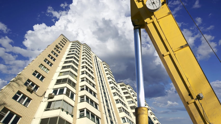 Part of a construction machine (excavator or crane) with multi-storey building under construction (new residential complex) on the background. Moscow, Russia  