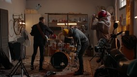 WIDE HANDHELD Friends playing music during their rock band rehearsal repetition inside a garage. Vocals, guitars and drums. Shot with 2x anamorphic lens - Powered by Shutterstock - Get 15% off with code: PIKWIZARD15