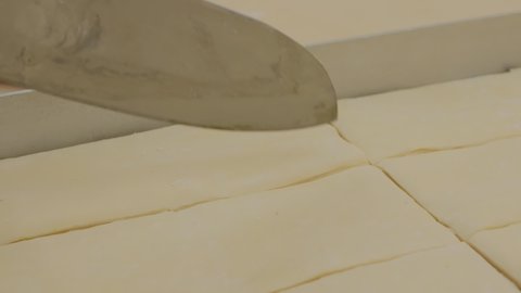 a baker demonstrates how many layers of dough the Turkish baklava has with a large knife. The pastry chef shows many layers of puff pastry with a knife for baking baklava.