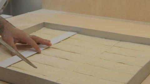 a baker uses a ruler to cut the dough for Turkish baklava. The pastry chef cuts the baklava blanks on a baking sheet before baking. Marks and cuts with a ruler