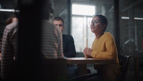 Project Manager Makes a Presentation for a Young Diverse Creative Team in Meeting Room in an Agency. Colleagues Sit Behind Conference Table and Discuss Business Development, Sales Analysis and Design. - Powered by Shutterstock - Get 15% off with code: PIKWIZARD15