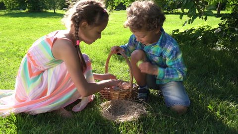 Two children boy and girl having easter egg hunt in garden backyard