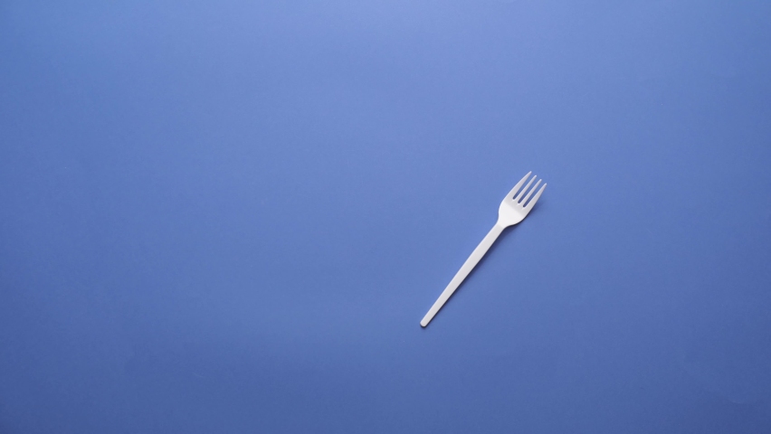 Many different plastic forks on color background, video with stop motion effect