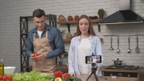Young attractive couple bloggers shooting video food vlog about cooking in the home kitchen. healthy food cooking concept