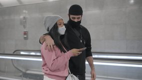A young interracial couple walking embraced in a subway corridor and talking about something they're seeing on their smart phone. - Powered by Shutterstock - Get 15% off with code: PIKWIZARD15