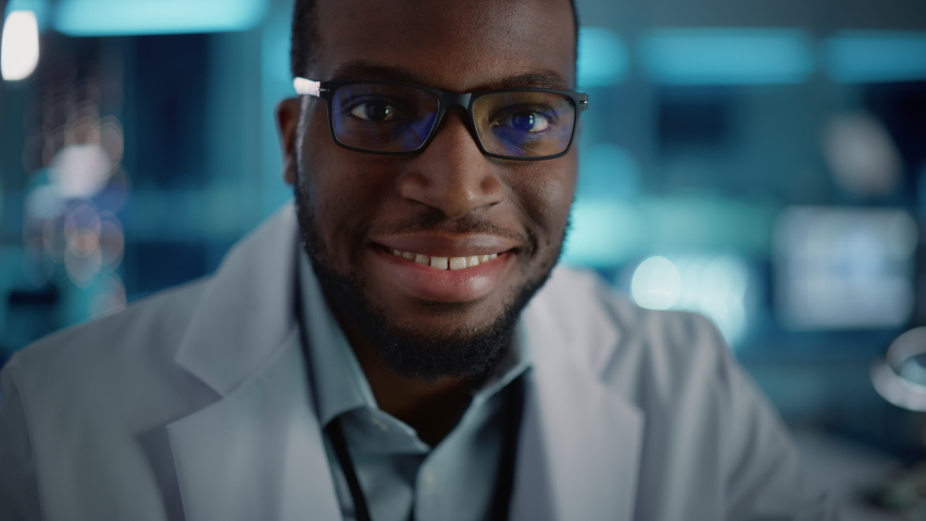 Handsome Black Man Wearing Glasses Smiling Charmingly Looking at Camera. Young Intelligent Male Engineer or Scientist Working in Laboratory. Technological Bokeh Blue Background. Close-up Shot | Shutterstock HD Video #1065341839