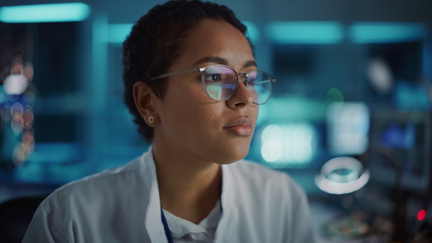 Beautiful Black Latin Woman Wearing Glasses Smiling Charmingly Looking at Camera. Young Intelligent Female Scientist Working in Laboratory. Technological Bokeh Blue Background. Close-up Shot Royalty-Free Stock Footage #1065341854