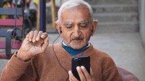Portrait of a happy Indian Grandfather is talking in videocall to relatives with a smartphone at home. Concept of technology, modern generation, family, connection, authenticity