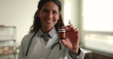 Woman cardiologist in white coat showing to camera bottle with cardiac medications pills, close up view. Vitamin complex sale discount, effective treatment, pharmacy, doctor prescribing drugs concept