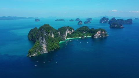 Aerial view of drone flying above amazing tropical island, bay, Steep cliffs and Longtail boats moving on beautiful turquoise water in Krabi Thailand.