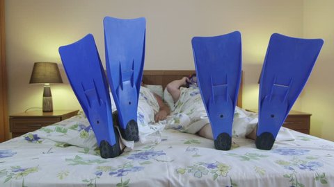 Funny couple wearing snorkeling equipment lying on bed ready for a summer beach vacations