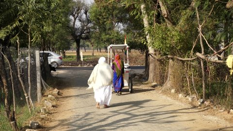 07 January 2021- Chomun, Jaipur, India. Holy Jain religion Followers walking through a village road. White ornamented dress is the symbol of calmness and Non violence in Jain Religion..