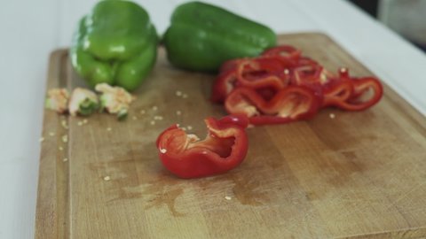 Hand cutting red peppers into pieces on a chopping board. Kitchen concept.