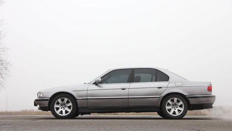 Chernigov, Ukraine - January 6, 2021: Car with headlights on. Old car BMW 7 Series (E38) on the road against a background of fog. Gloomy weather. Bmw and fog