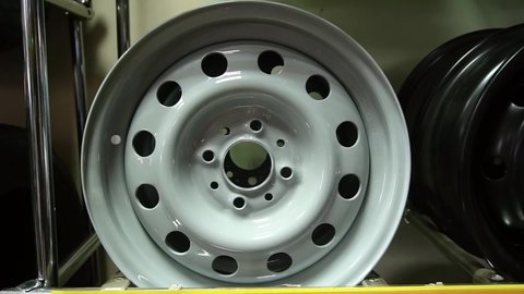 A gray new car rim sits on a shelf in an auto parts store. A wheel in a car shop.