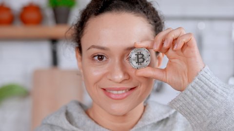 portrait adult happy woman have fun holding bitcoin token coins posing with smile at home