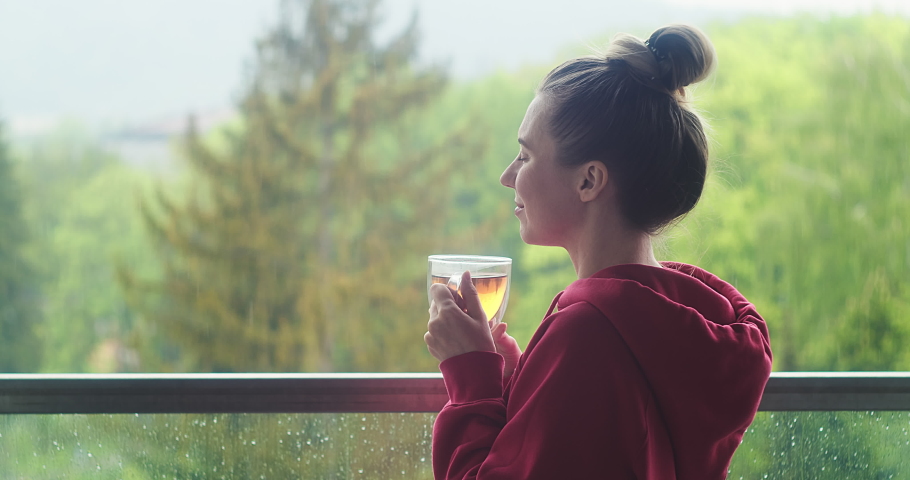 Woman drinks tea a cup, and relax on terrace at home in autumn rainy day. Health care, authenticity, sense of balance and calmness. Work from home. 4K Video | Shutterstock HD Video #1065368395