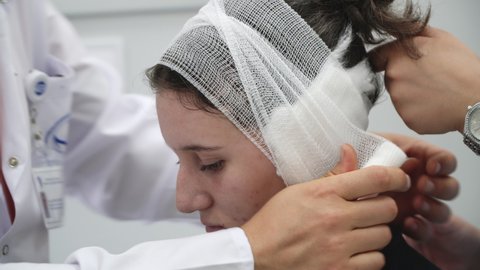 Doctor makes a bandage on head patient at clinic after ear surgery