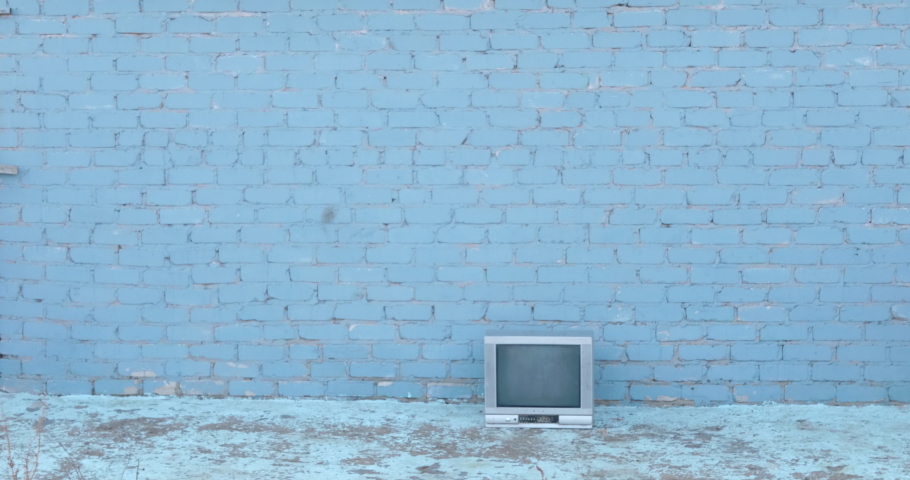 Two Caucasian brothers are playing in yard with grocery cart. Children put old TV in it and roll each other