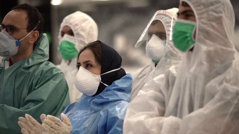 a group of female and male health care staff with face mask and protective gear and gloves clapping for medical staff support during coronavirus pandemic time. portrait of men and women