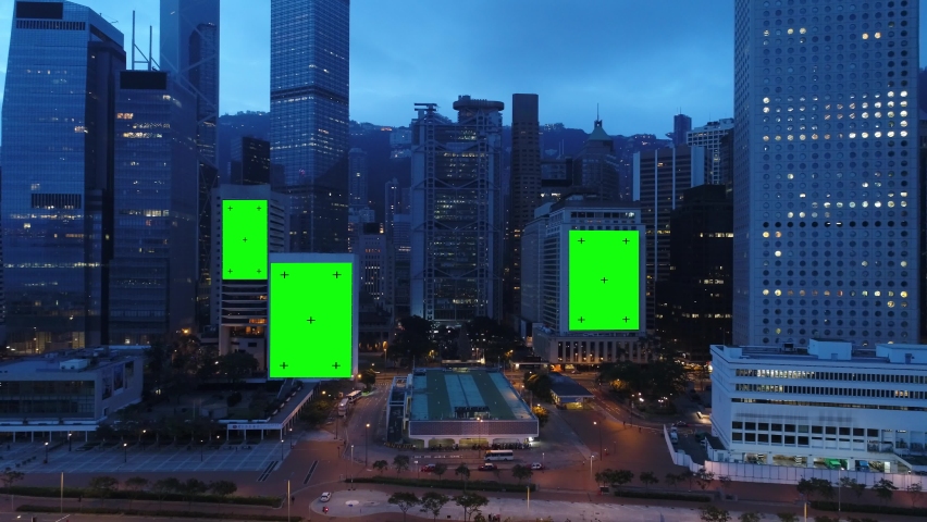 AERIAL. Top view of skyscrapers and green screen build board with tracking point. Bird view of modern city at night streets.