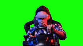 Asian gamer man playing game and wearing vr glasses with isolated green blackground. Asian man controlling with driver console and smart glasses. Young man play racing game with green screen.