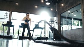 Beautiful Asian girl wearing Sports bra Black is practicing battle rope in the gym exercise concept slow motion video.