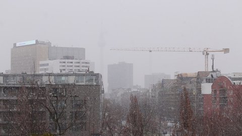 Berlin, Germany 1-11-2021 View of the Axel-Springer-Hochhaus on the left, and a crane in a construction site during snowfall. Cityscape in the German Capital during a snowy and cold winter afternoon